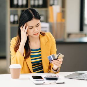 Asian business woman is stressed, bored, and overthinking from working on a tablet at the modern office.