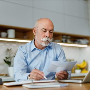 Focused senior male writing one letter.