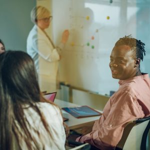Happy multiracial business team working together at corporate briefing gathered at table in the conference room. Smiling diverse colleagues discussing business. Focus on an african american man.